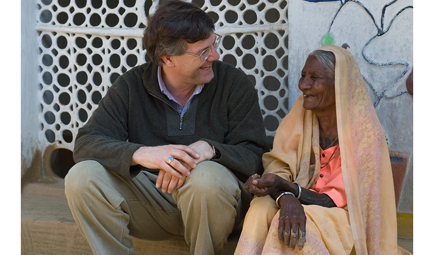 photo of the subject sitting on steps next to a older woman and having a laugh together